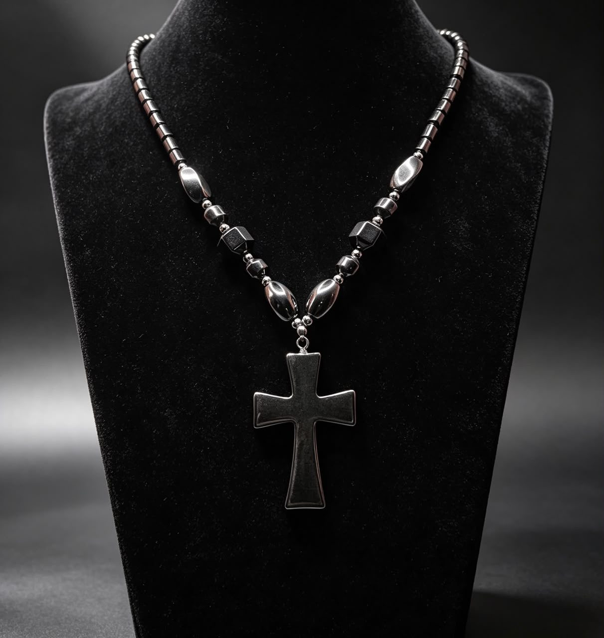 The Obsidian Cross Necklace on black velvet display bust